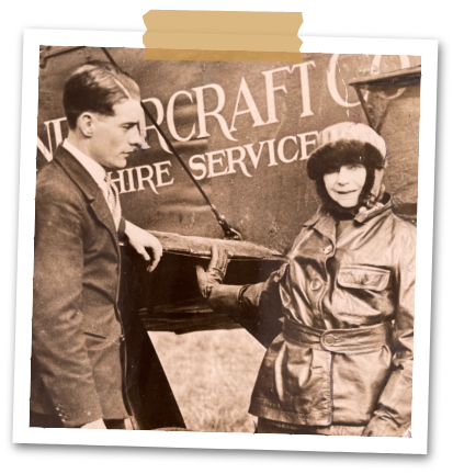 A man with a woman pilot standing touching a plane